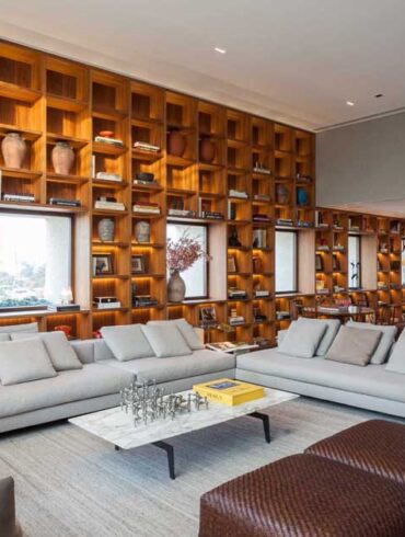 a-full-wall-bookshelf-with-led-lighting-frames-the-windows-like-artwork-in-this-apartment