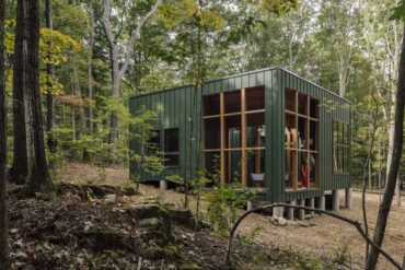 a-green-exterior-helps-this-cabin-blend-into-the-forest