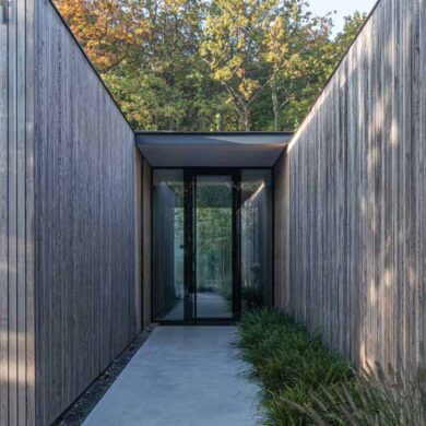 an-exterior-of-vertical-wood-siding-helps-this-house-blend-into-the-surrounding-forest