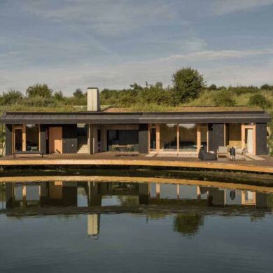 this-small-home-with-a-green-roof-curves-around-a-pond